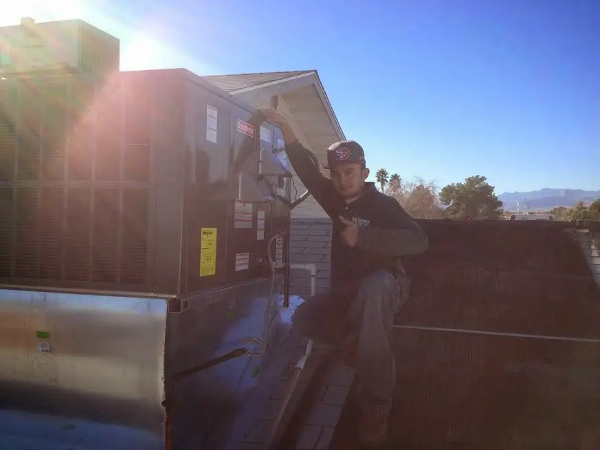 HVAC technician performing AC Tune-Up on a rooftop unit in Hartland